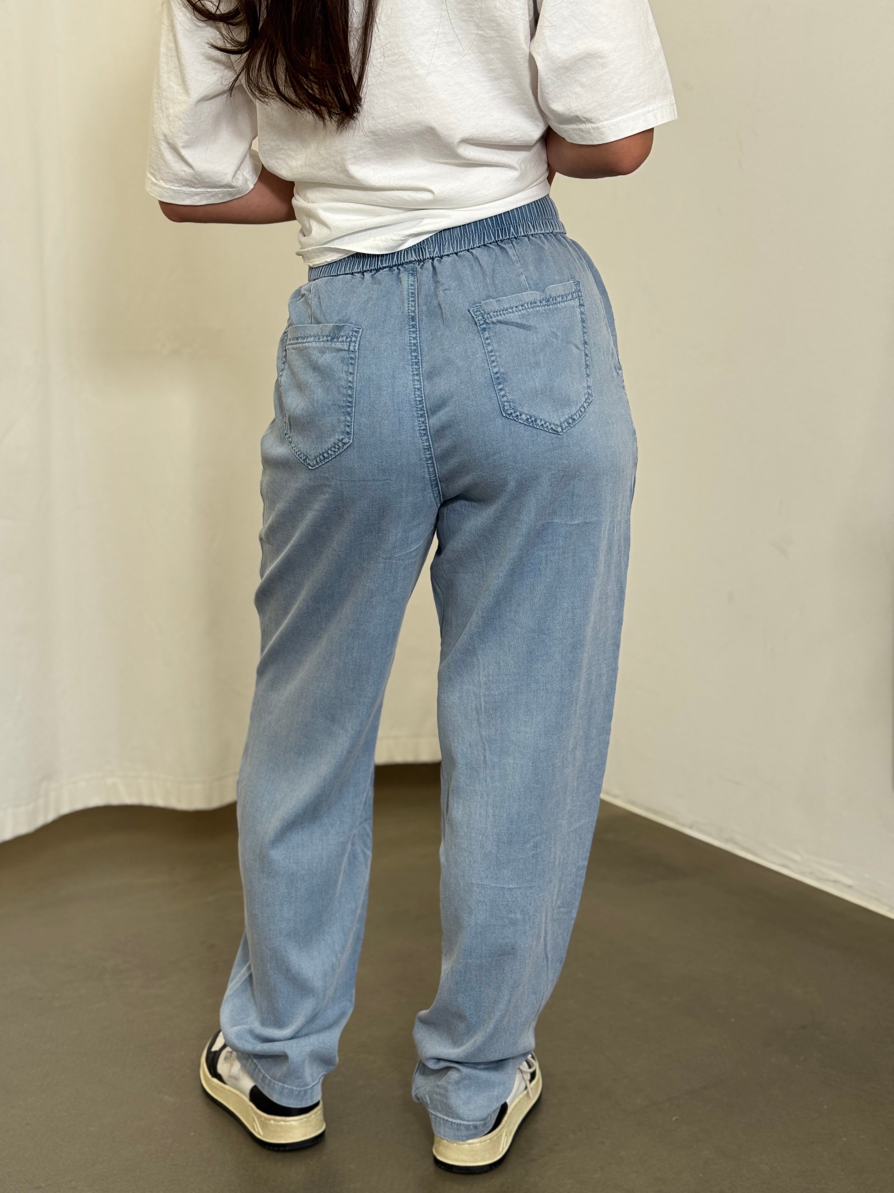 Stylischer O-Shape Look mit hellblauer Hose und Sneakern von hinten