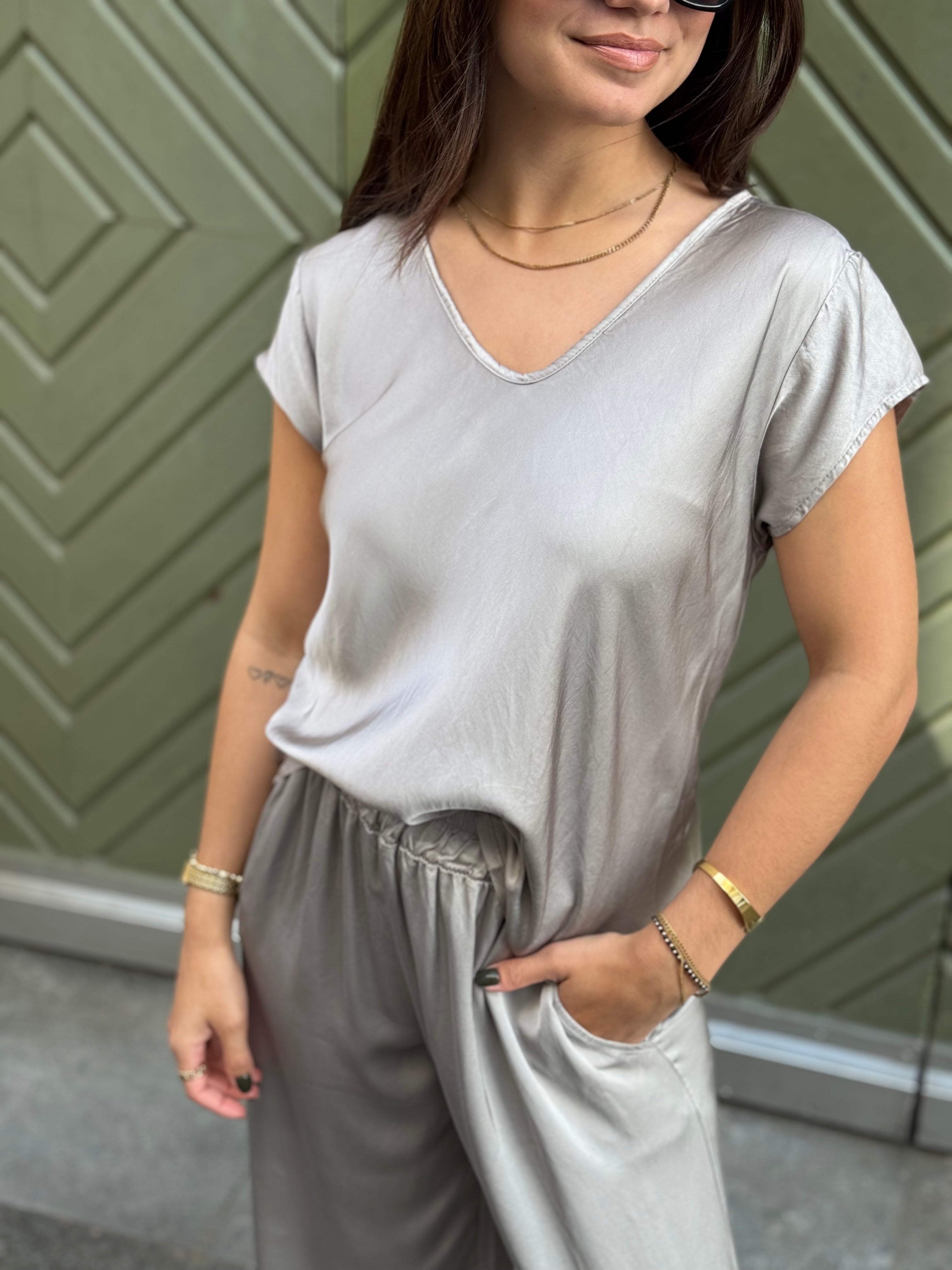 Frau trägt elegantes V-Ausschnitt Shirt aus Satin in Hellgrau – modern & lässig